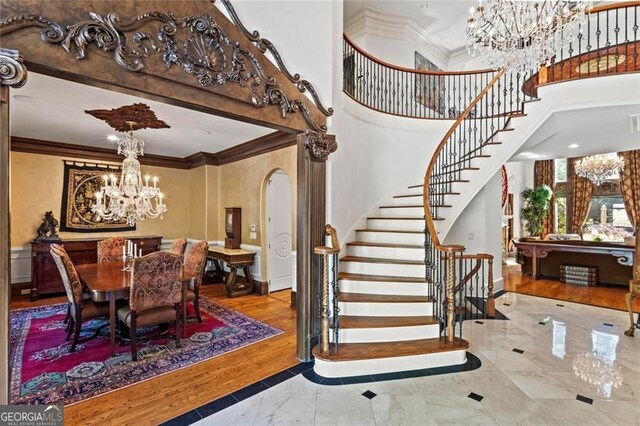 2120 Blackheath Trce, Alpharetta, GA 30005 - stairway featuring a chandelier, crown molding, marble tiled flooring, arched walkways, and a high ceiling