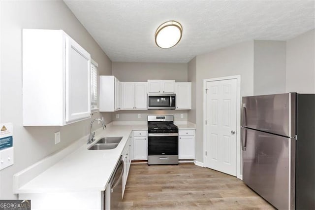 kitchen with white cabinets, light countertops, a sink, and appliances with stainless steel finishes