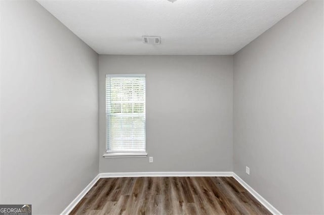 empty room with visible vents, baseboards, and dark wood-type flooring