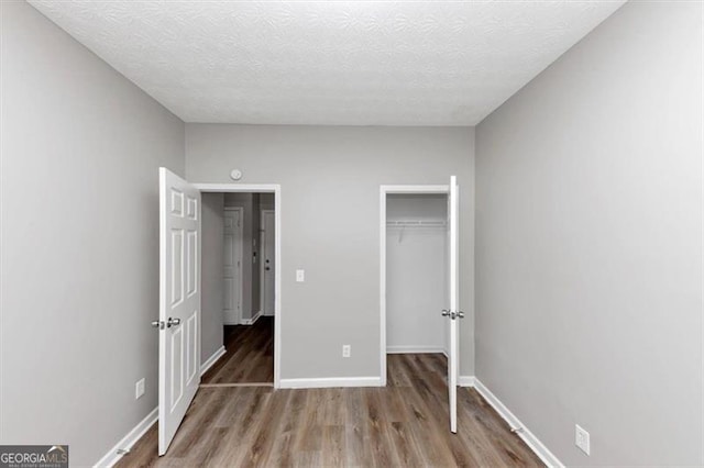 unfurnished bedroom with baseboards, wood finished floors, a textured ceiling, and a closet