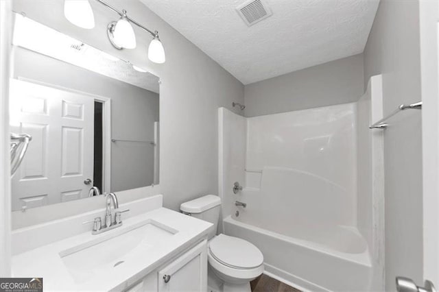 bathroom featuring visible vents, toilet, vanity, tub / shower combination, and a textured ceiling