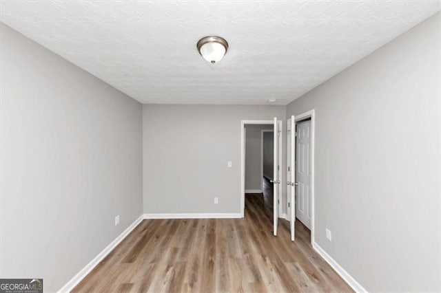 unfurnished bedroom with baseboards, light wood-style floors, and a textured ceiling
