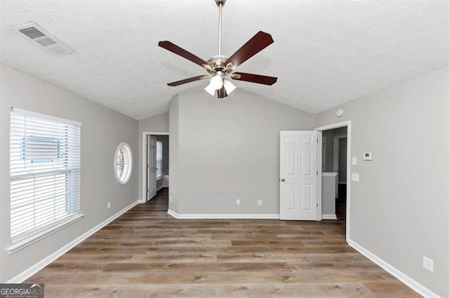 interior space with vaulted ceiling, wood finished floors, visible vents, and baseboards
