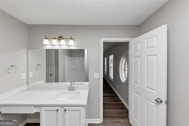 bathroom featuring baseboards, wood finished floors, a textured ceiling, and vanity