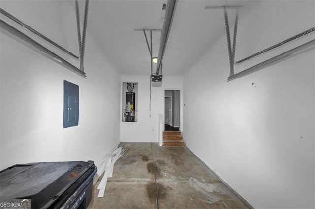 garage featuring electric panel, water heater, and a garage door opener