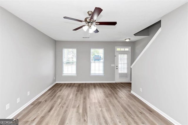 unfurnished living room with baseboards, a ceiling fan, wood finished floors, and visible vents