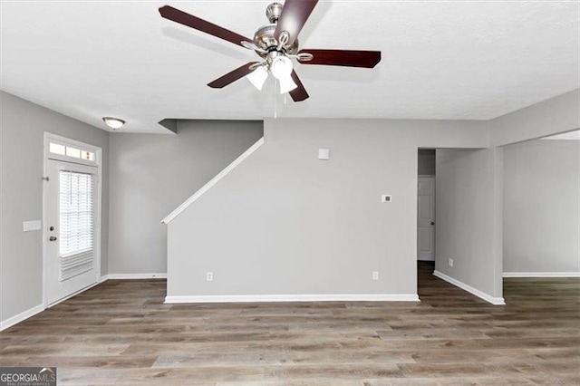 unfurnished living room featuring wood finished floors, a ceiling fan, and baseboards