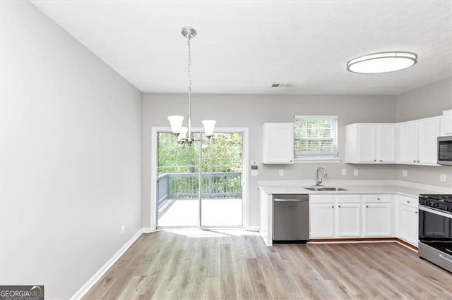 kitchen featuring a sink, light wood finished floors, light countertops, white cabinets, and appliances with stainless steel finishes