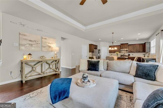 living area featuring recessed lighting, dark wood finished floors, ornamental molding, baseboards, and ceiling fan with notable chandelier