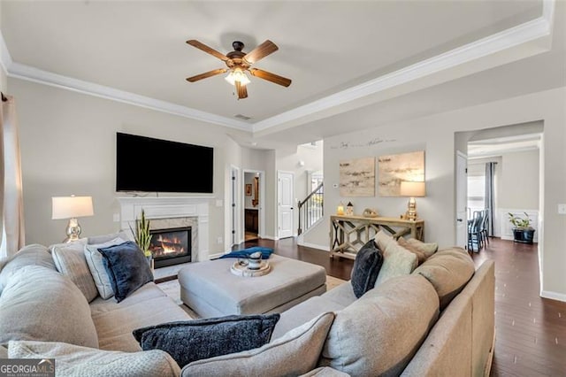 living room with a ceiling fan, a premium fireplace, crown molding, stairs, and dark wood-style flooring