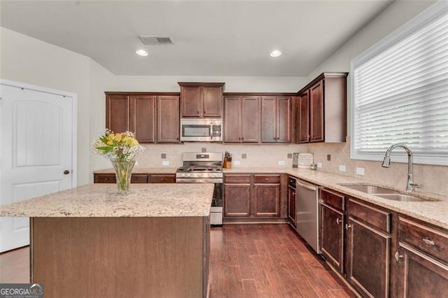 kitchen featuring a sink, dark wood finished floors, visible vents, light stone countertops, and appliances with stainless steel finishes