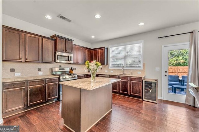 kitchen with stainless steel appliances, wine cooler, visible vents, a sink, and tasteful backsplash