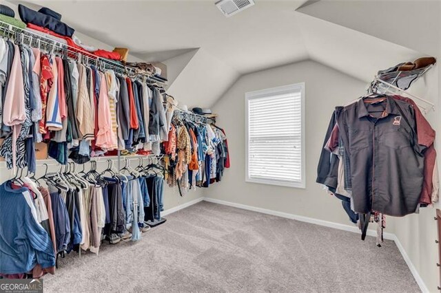 spacious closet with lofted ceiling, visible vents, and carpet flooring