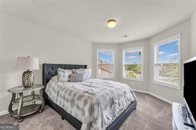 carpeted bedroom featuring visible vents, baseboards, and multiple windows