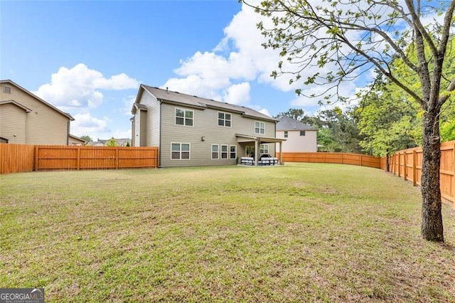 rear view of house featuring a yard and a fenced backyard