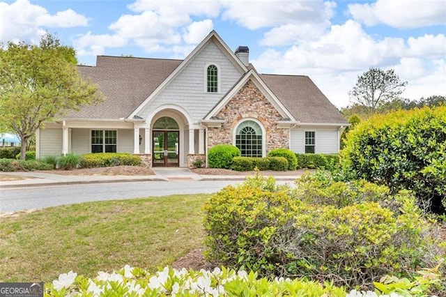 view of front of house featuring stone siding, a chimney, french doors, and a front yard