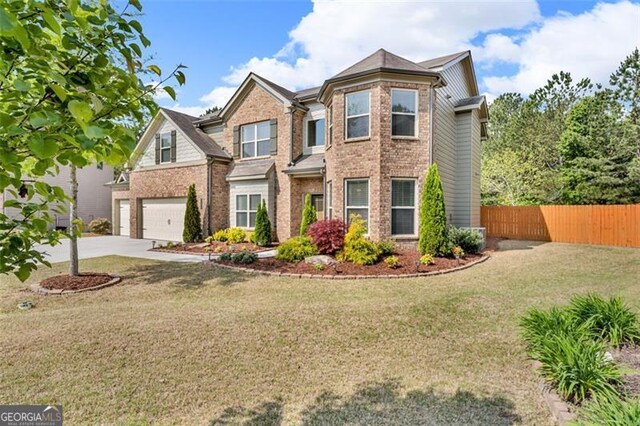 view of front of home featuring concrete driveway, a front lawn, fence, a garage, and brick siding