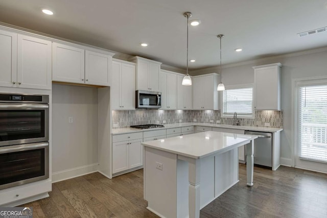 7208 Whitewater Dr, Flowery Branch, GA 30542 - kitchen with appliances with stainless steel finishes, white cabinetry, dark wood-type flooring, backsplash, and light countertops