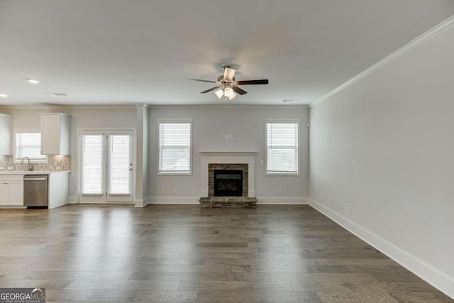 7208 Whitewater Dr, Flowery Branch, GA 30542 - unfurnished living room with ceiling fan, ornamental molding, plenty of natural light, a fireplace, and dark wood-style flooring