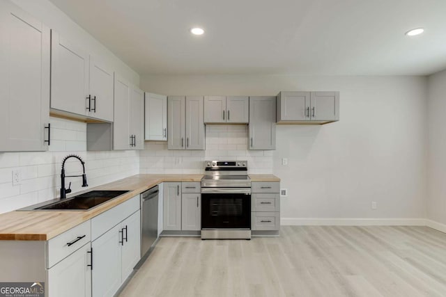7208 Whitewater Dr, Flowery Branch, GA 30542 - kitchen with stainless steel appliances, butcher block countertops, light wood finished floors, backsplash, and recessed lighting