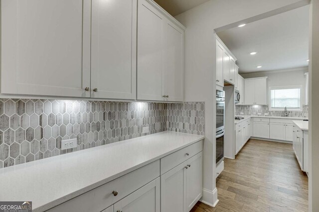 7208 Whitewater Dr, Flowery Branch, GA 30542 - kitchen with decorative backsplash, light countertops, light wood-type flooring, white cabinetry, and recessed lighting