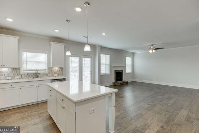 7208 Whitewater Dr, Flowery Branch, GA 30542 - kitchen with crown molding, ceiling fan, light countertops, a kitchen island, and backsplash