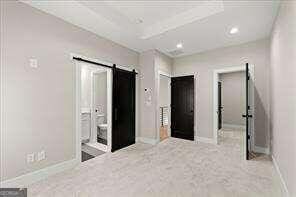 carpeted empty room with baseboards, recessed lighting, and a barn door