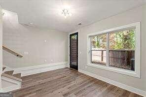 unfurnished living room featuring baseboards, stairs, and wood finished floors