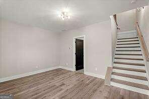 interior space with baseboards, wood finished floors, and stairway
