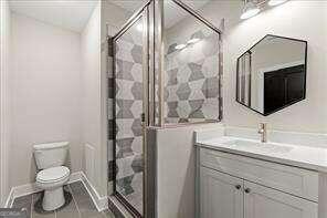 full bathroom with vanity, tile patterned floors, a shower stall, and toilet