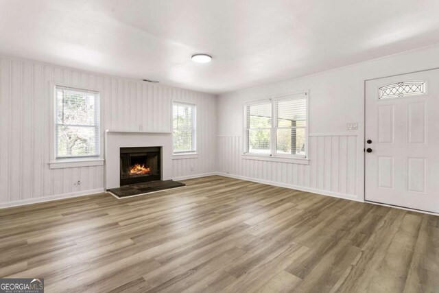 3556 Finch Rd SW, Powder Springs, GA 30127 - unfurnished living room featuring wood finished floors, a lit fireplace, a decorative wall, and a wainscoted wall