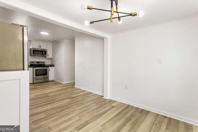 3556 Finch Rd SW, Powder Springs, GA 30127 - unfurnished living room with light wood finished floors, baseboards, and a chandelier