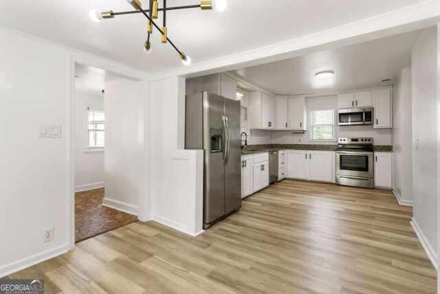 3556 Finch Rd SW, Powder Springs, GA 30127 - kitchen with appliances with stainless steel finishes, light wood finished floors, a chandelier, and plenty of natural light