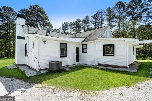 3556 Finch Rd SW, Powder Springs, GA 30127 - back of house with cooling unit, a yard, a chimney, and a shingled roof