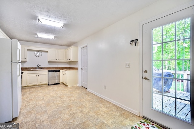 kitchen featuring a sink, a textured ceiling, dishwasher, baseboards, and freestanding refrigerator