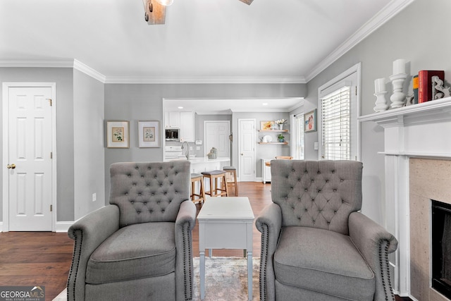 living area with baseboards, crown molding, and wood finished floors