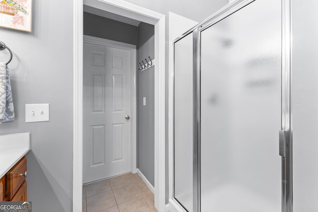 bathroom featuring tile patterned floors, baseboards, vanity, and a shower stall