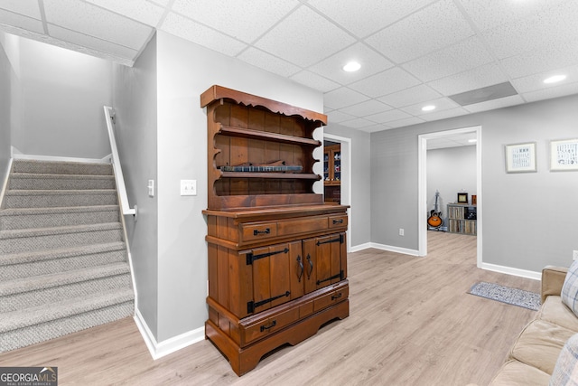 stairway with baseboards, wood finished floors, a drop ceiling, and recessed lighting