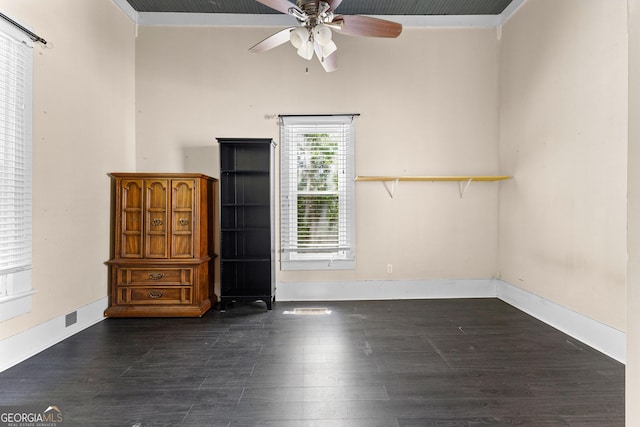 spare room with a ceiling fan, baseboards, and dark wood finished floors