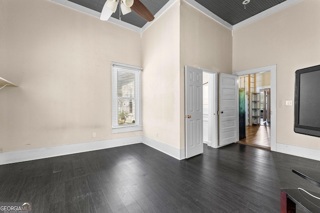 interior space featuring dark wood-type flooring, a high ceiling, a ceiling fan, and baseboards
