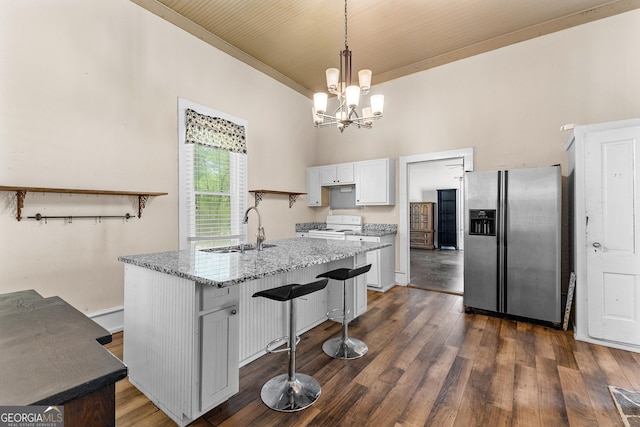 kitchen with a sink, a chandelier, stainless steel fridge with ice dispenser, white cabinets, and light stone countertops