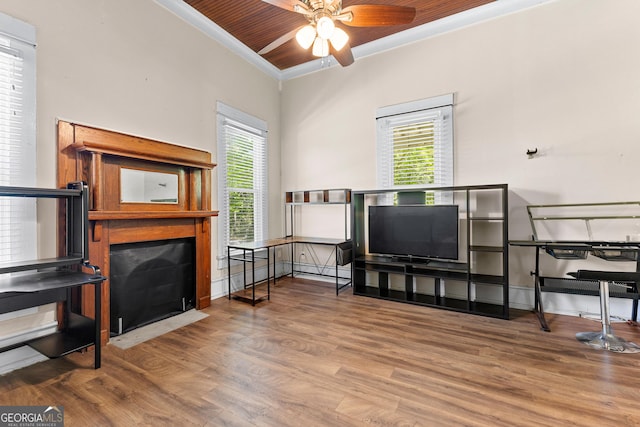 living area featuring baseboards, a ceiling fan, wood finished floors, and a healthy amount of sunlight