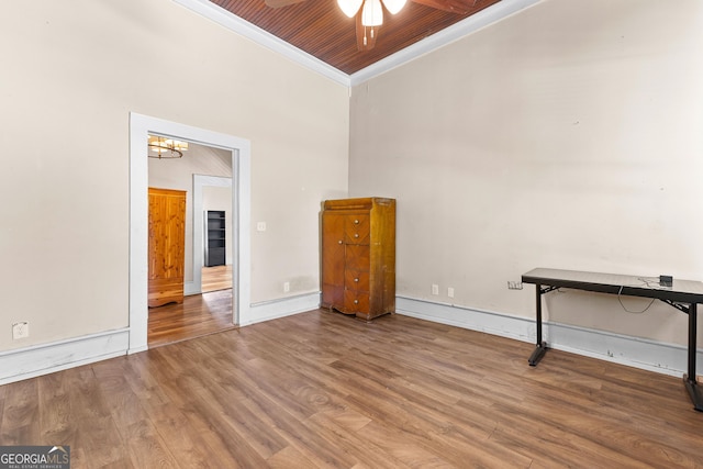 interior space with a high ceiling, ornamental molding, wood finished floors, and ceiling fan with notable chandelier
