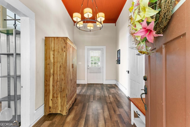 entryway with dark wood finished floors, a high ceiling, baseboards, wood ceiling, and a notable chandelier
