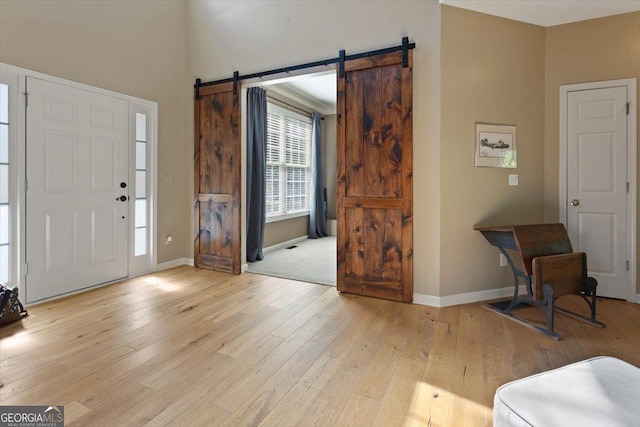 foyer with baseboards, a barn door, and light wood-style flooring