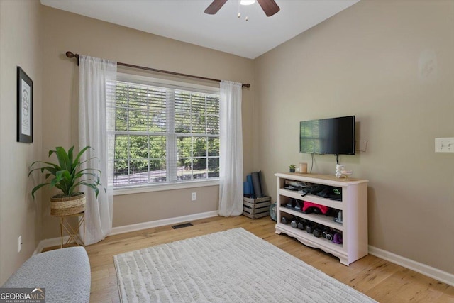 living room featuring visible vents, a ceiling fan, baseboards, and light wood-type flooring
