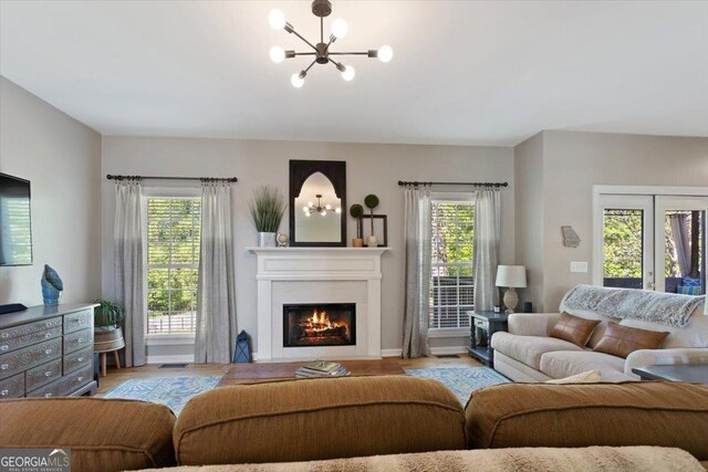 living area with a notable chandelier, a wealth of natural light, and wood finished floors