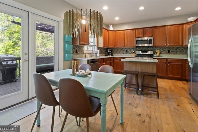 kitchen featuring backsplash, light wood-type flooring, light countertops, a sink, and stainless steel appliances