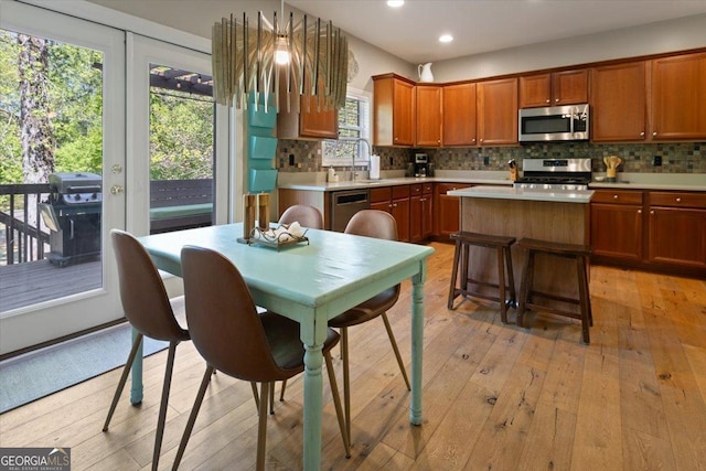 kitchen with light countertops, stainless steel appliances, backsplash, and light wood-type flooring