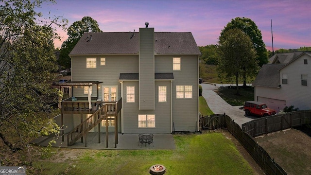 back of property with fence, a pergola, a chimney, concrete driveway, and a lawn